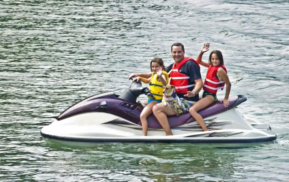 family waving on a jet ski